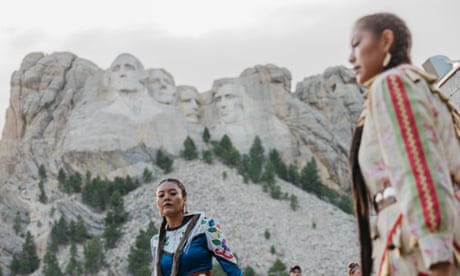 Sunni Begay (dark blue) and Dion Tapahe (yellow) of the Jingle Dress Project dance at Mount Rushmore. They were invited by Red Dawn Foster, a state senator representing the Pine Ridge area.