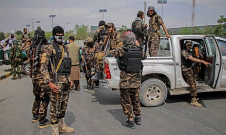 Taliban fighters in combat gear mill around a pickup truck