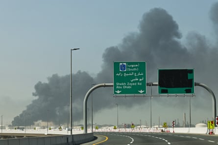 Empty road and traffic sign in Arabic with smoke plume behind