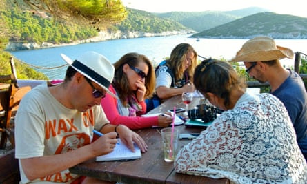 people writing on a table by the water