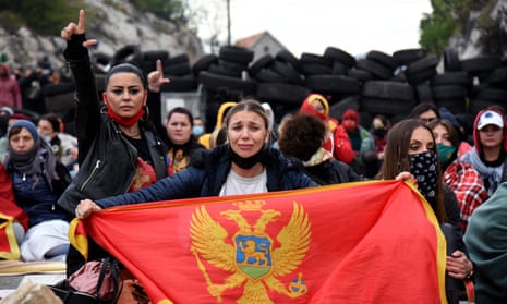 Demonstrators with the flag of Montenegro in front of a barricade of car tyres