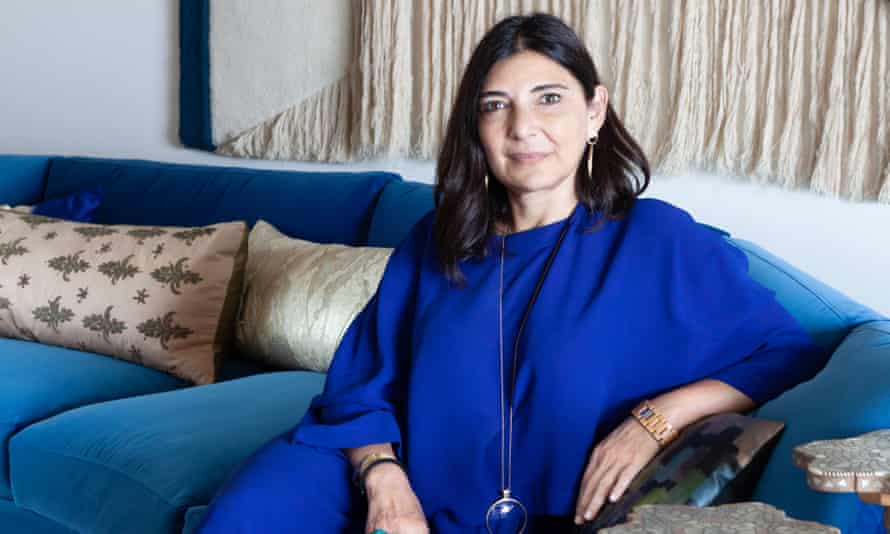 Designer Nada Debs wearing blue, sitting on a curved blue sofa