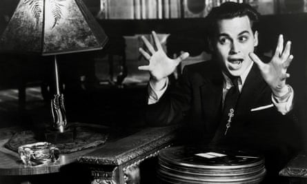 A black and white still of a man holding his hands up.