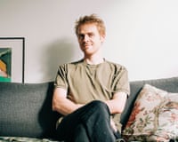 Kiran Leonard sits with legs crossed on a grey sofa