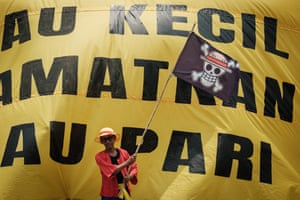 A man waving a skull-and-crossbones flag in front of a huge yellow banner