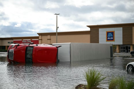 red and white overturned truck in floodwater outside of aldi store