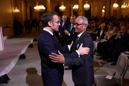 Emmanuel Macron and Ali Akbar grasp one another’s arms in a ceremony at the Élysée Palace in Paris.
