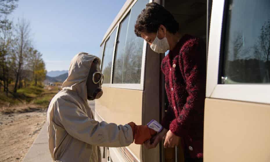 A 'hygienic and anti-epidemic official' checks the body heat of a traveller aboard a bus as part of preventative measures against coronavirus, at a roadblock at the entrance to Wonsan, Kangwon province