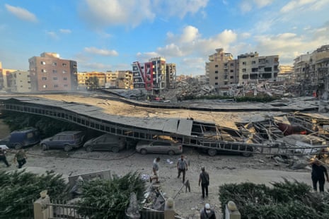 People stand near a collapsed multi-storey car park after a bombing.