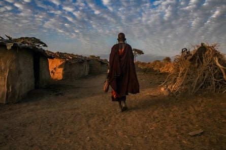 A woman walks across a rural landscape at dawn