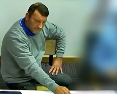 Paul Quinn in a grey sweatshirt sits at a table during a police interview