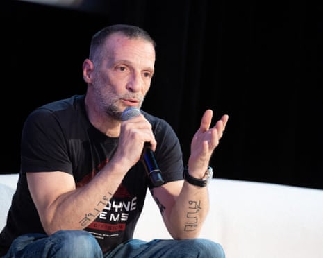 Mathieu Kassovitz sat on stage and speaking into a microphone during a film festival