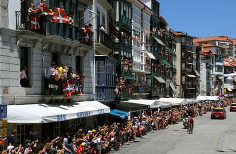 Ikurrina flags flutter as Laurent Pichon and Neilson Powless race through the streets of the Basque coastal town of Lekeitio.