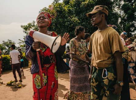 A woman with a megaphone stands next to a soldier