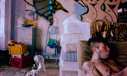 Barry Keoghan, heavily tattooed as the father, Bug, sits in a messy room covered in graffiti.
