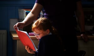 A teaching assistant helps a child to read