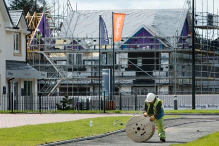 A construction worker rolls a cable drum on a new housing estate