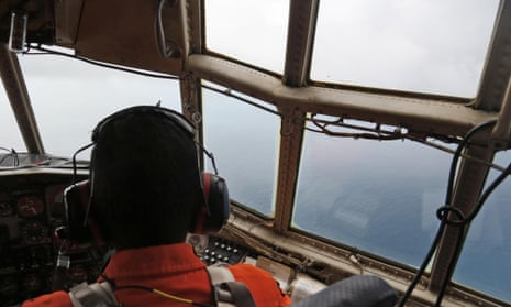 A crew of an Indonesian Air Force C-130 airplane of the 31st Air Squadron scans the horizon during a search operation for the missing AirAsia flight 8501 jetliner over the waters of Karimata Strait in Indonesia.