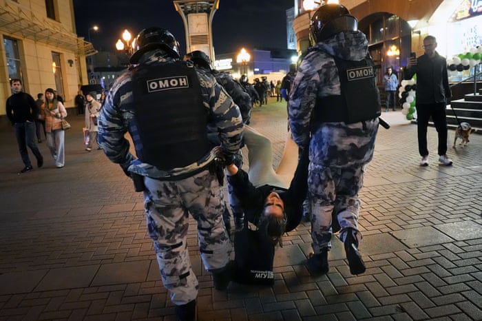 Riot police drag away a protester in Moscow last night.