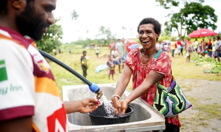A woman washes her hands at the running water station which was set up as a requirement to keep the Gunanur market running in accordance with state of emergency measures cross East New Britain province, Papua New Guinea.