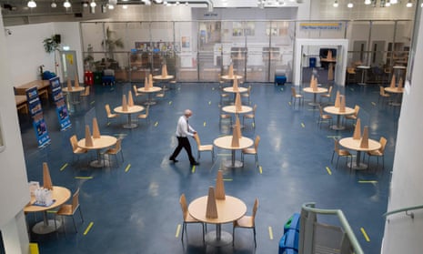 A member of staff at the University of Bolton inspects a communal workspace with socially distanced seating and perspex screens before students return next week.