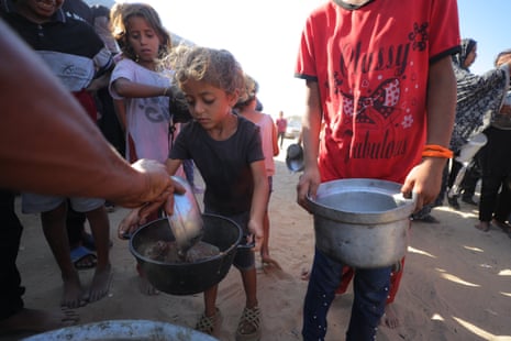Palestinians who are struggling to access food due to ongoing Israeli attacks receive hot meals distributed by a charity organisation at Nuseirat refugee camp in Gaza City on 29 September.