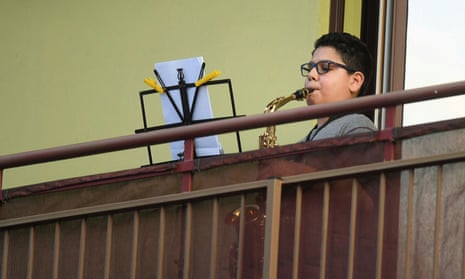 Day five of Italy's nationwide coronavirus lockdown, in Rome<br>A boy plays the saxophone from a balcony during a flash mob to raise morale as Italian government continues restrictive movement measures to combat the coronavirus outbreak, in Milan, Italy March 14, 2020. REUTERS/Daniele Mascolo