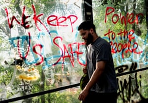 A man walks by graffiti on a pedestrian bridge reading “We keep us safe” and “Power to the people”.