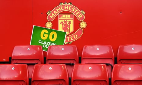 A 'Glazers out' protest poster in front of the red Manchester United logo behind stadium seating.