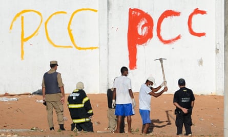 Corpses are dug out beneath PCC graffiti in the Alcacuz penitentiary after a fight between rival gangs left at least 30 prisoners dead near Natal, in the Brazilian north-east, in 2017.