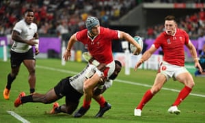 Wales??? centre Jonathan Davies passes the ball to Wales??? wing Joshua Adams after being tackled by Fiji???s wing Josua Tuisova.