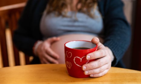 A close up view of a pregnant woman having a cup of tea