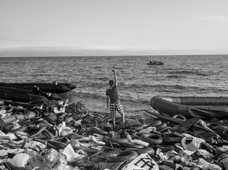 Lesbos, Greece, September 29, 2015. A refugee indicates the landing area to an approaching inflatable raft as it approaches Assos, Turkey. More than 2,100 people have died trying to make this crossing.