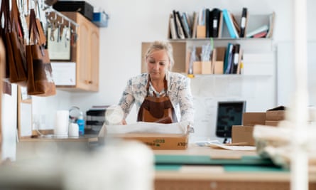 Independent Business Owner Packing ProductsA medium front close-up view of a female tannery owner in her studio workspace packing her eco-friendly leather handbags. She is committed to a circular economy using eco-friendly packaging and recycled packaging. / Female Focus Collection