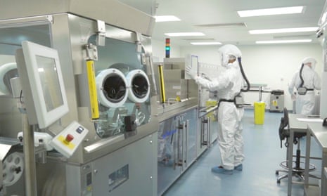 Two people in a lab wearing protective clothing