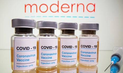 Vials and medical syringe are seen in front of Moderna logo