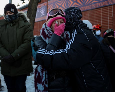 Women embrace, one covering her hand with her mouth