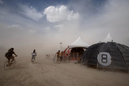 People bike away from a dust storm