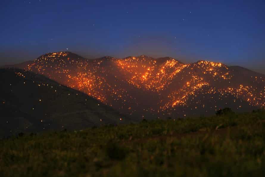 A mountain landscape is aglow with thousands of spot fires.