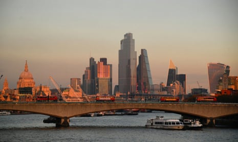 St. Paul’s Cathedral and buildings of the City of London financial district are seen as buses cross Waterloo bridge at sunset