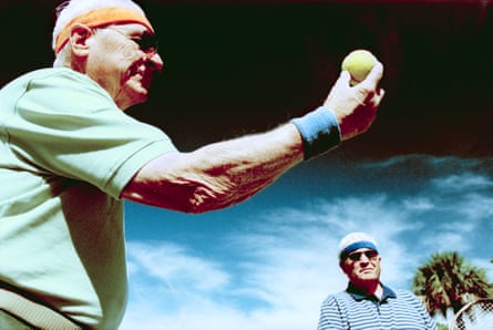 Two older men play tennis.