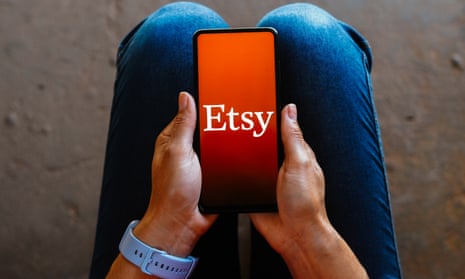 the etsy logo on a smartphone held in hands rested upon a person's knees