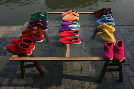 Three rows of slippers placed on top of a table in varying colours