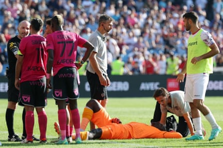 Clermont goalkeeper Mory Diaw lies on the floor surrounded by players and medical staff