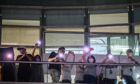 Apple Daily employees shine their phone torches in response to supporters below as the last edition went to press on 23 June.