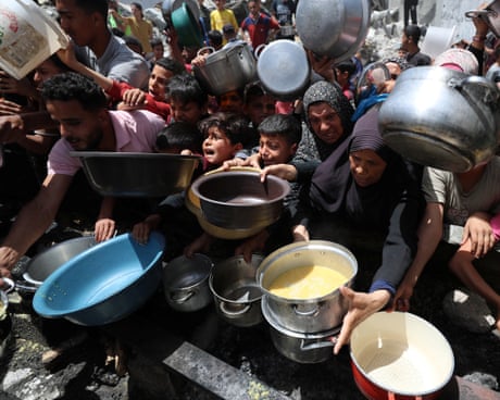Palestinians hold pans as they wait to receive food cooked by a charity kitchen