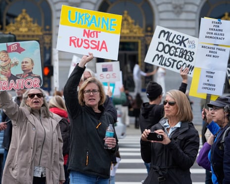 People hold up signs to protest the Trump administration in San Francisco.