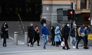 People wearing face masks cross the road outside Flinders Street station