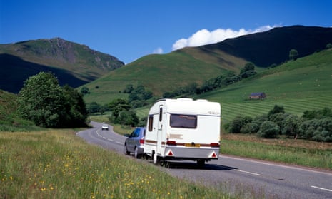 Car with caravan driving along A470 with green hills and trees in background.