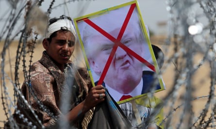 A demonstrator at the Israel-Gaza border in southern Gaza holds a poster of Donald Trump emblazoned with a red cross